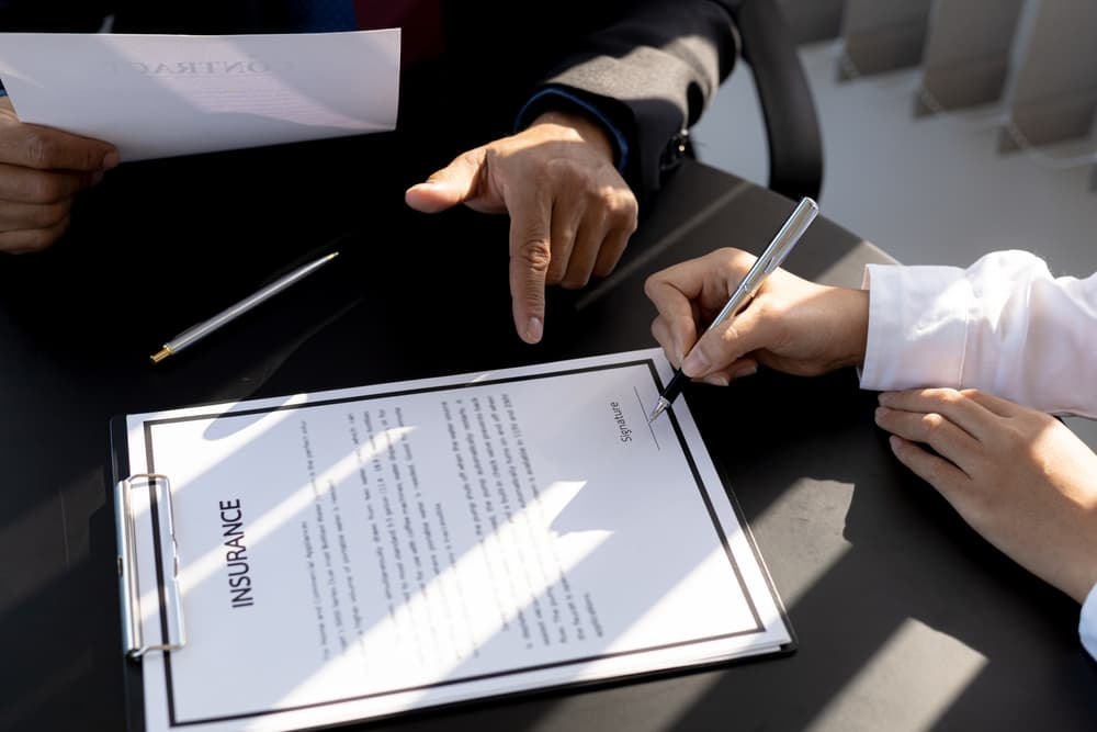 An insurance agent and a customer sign an agreement with the insurance company, finalizing the terms and benefits of the policy.