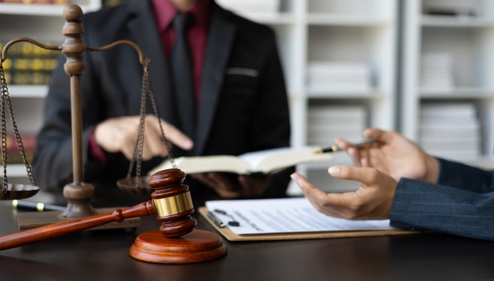 A businessman and a lawyer consult with a legal advisor in a law office, focusing on legal and justice consulting services.