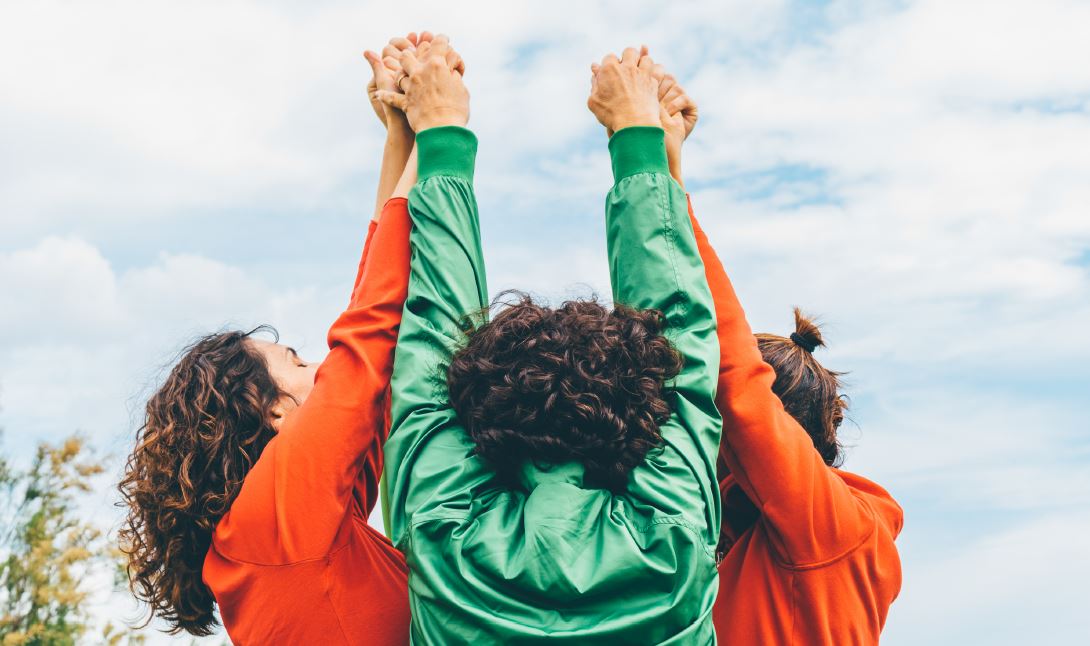 three girls hold hands in a tight circle of excitement