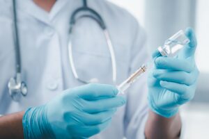 Doctor in laboratory holding a syringe with liquid vaccines